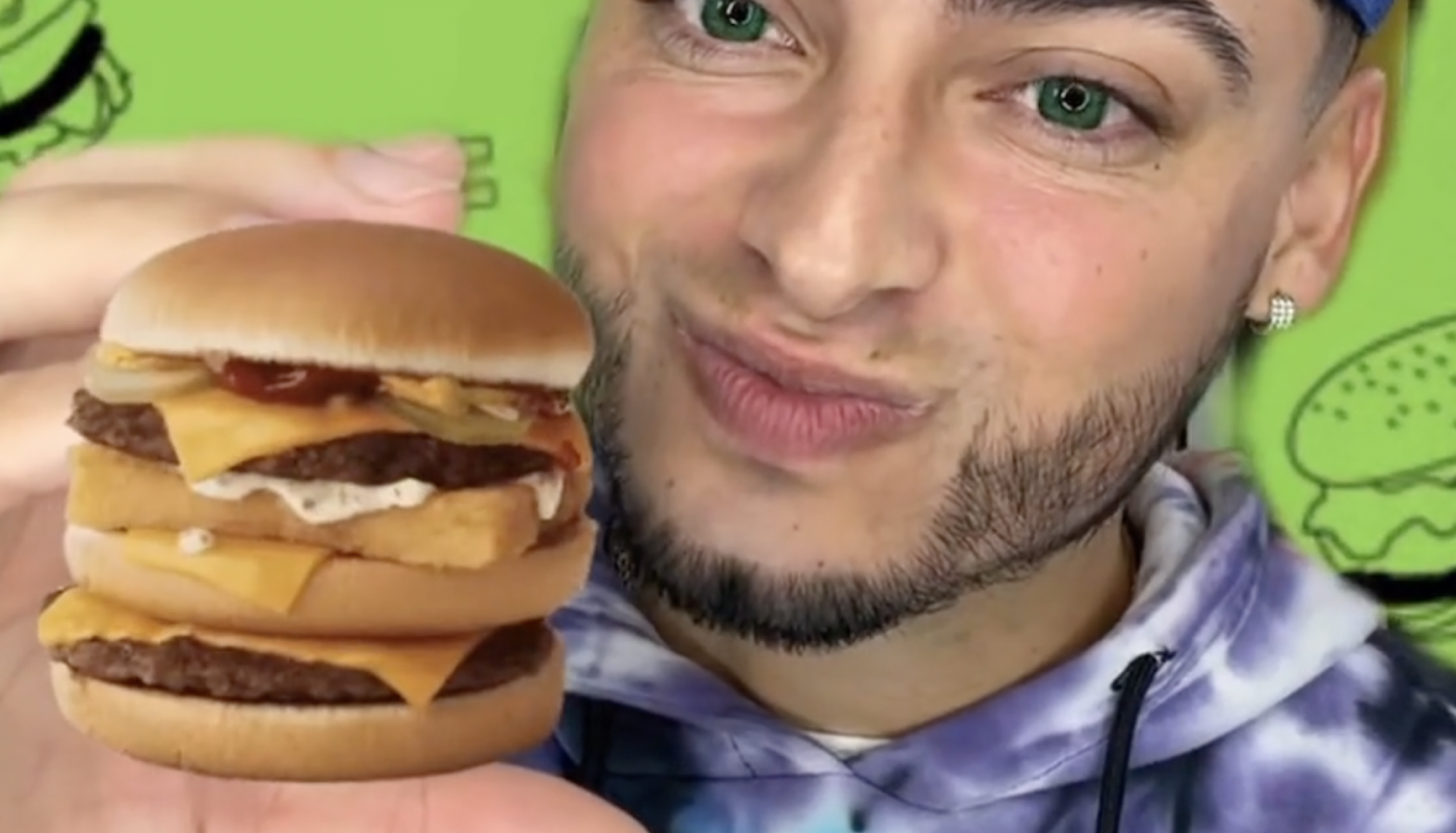 Person holding image of McDonalds 'Menu Hack' special burger stacked tall