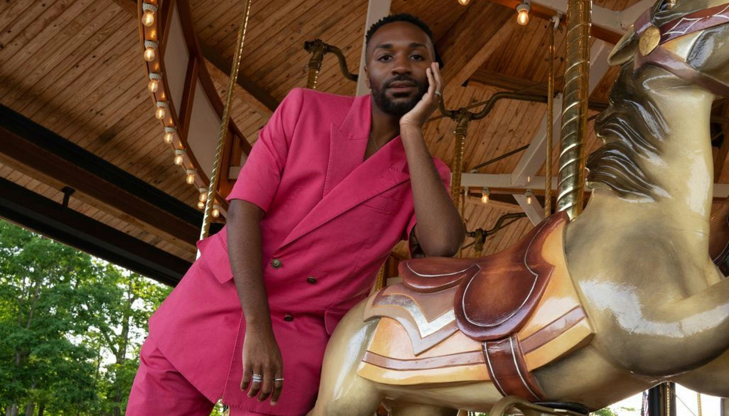 ESSENCE Festival of Culture featuring black Influencer wearing pink outfit leaning against horse on carousel.
