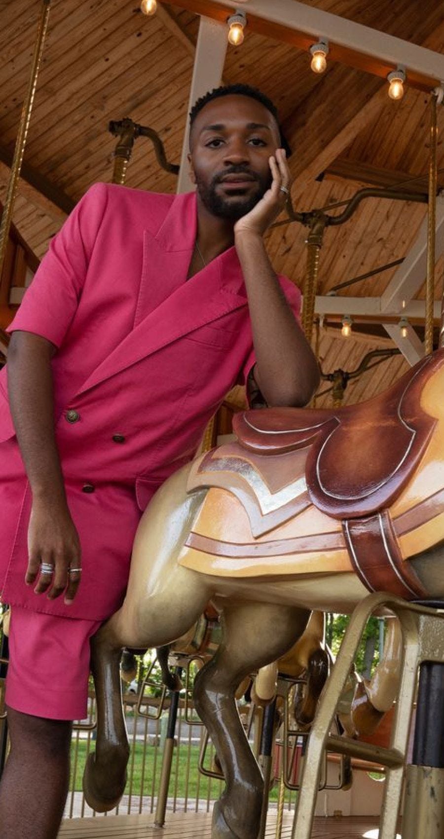 ESSENCE Festival of Culture featuring black Influencer wearing pink outfit leaning against horse on carousel.